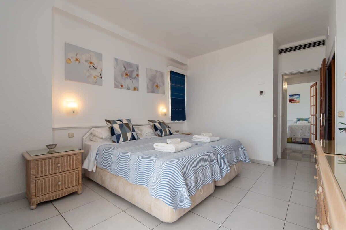 A bedroom with a large bed, a bedside table, and wall-mounted lights.