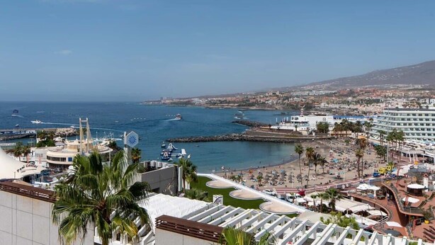Un paysage urbain côtier avec un port de plaisance, une plage et des bâtiments d’hôtel.