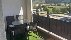 Un balcon avec une table et des chaises, d’où l’on peut admirer la vue sur la ville et les montagnes.
