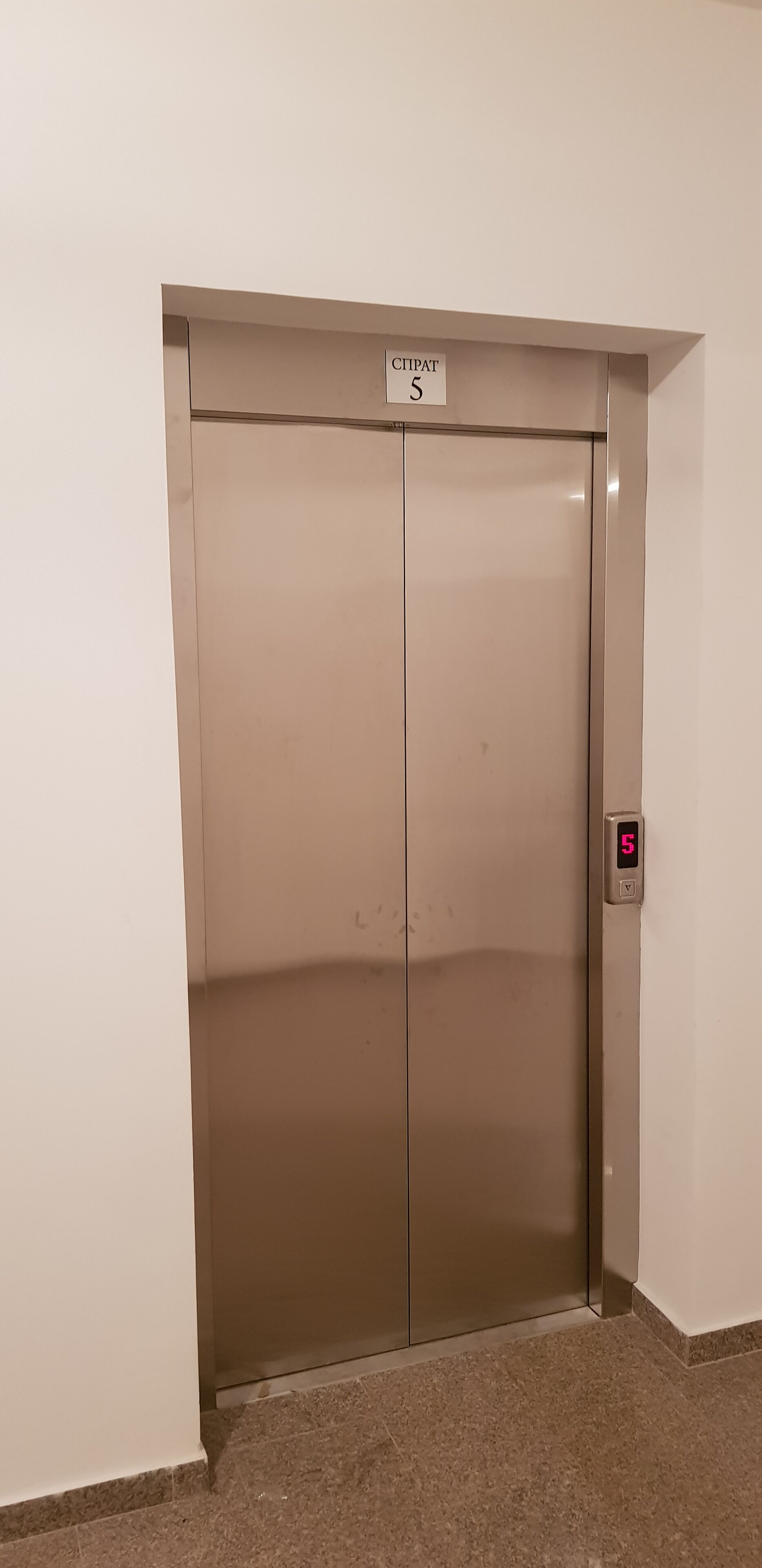 An elevator with a sign indicating it is the fifth floor.