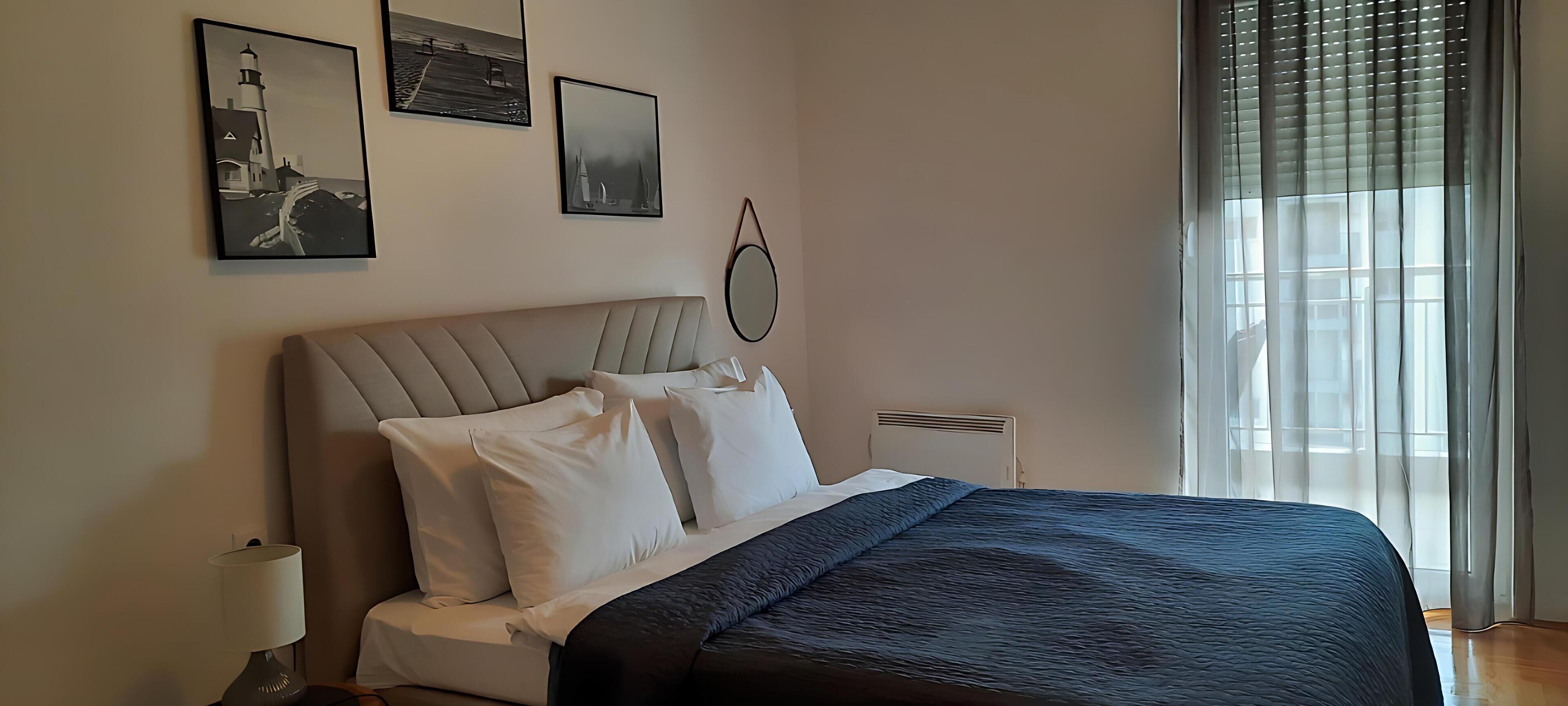 Un dormitorio con una cama, una mesita de noche, una lámpara y dos cuadros en la pared.