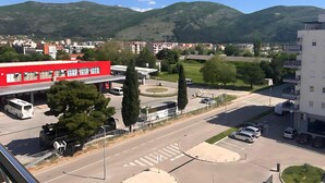 Un bâtiment rouge abritant une station-service, un parking et une route où circulent des véhicules.