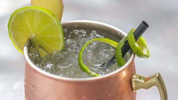 A copper mug with a handle, filled with ice and garnished with lime slices and a lime wedge.