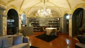 A luxurious interior with a high arched ceiling, ornate gold detailing, a chandelier, a wine cellar, and a cozy seating area. - Mery Bistrot in Villa Bisbini (Marano sul Panaro)