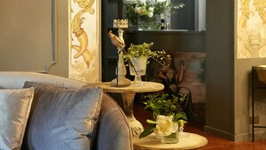 A room with a sofa, a round table with a vase, and an ornate archway. - Mery Bistrot in Villa Bisbini (Marano sul Panaro)