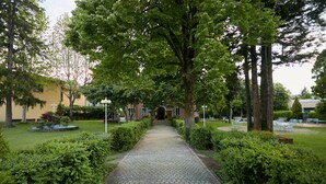A paved pathway flanked by neatly trimmed hedges and trees, leading to a building entrance. - Mery Bistrot in Villa Bisbini (Marano sul Panaro)