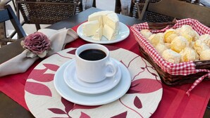 Una mesa dispuesta con un plato de queso, una taza de café y una cesta de panecillos.