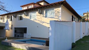 Una casa de dos pisos con piscina, patio cercado y zona de patio.