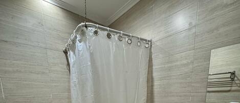 A bathroom with a shower curtain, toilet, sink, and tiled walls.