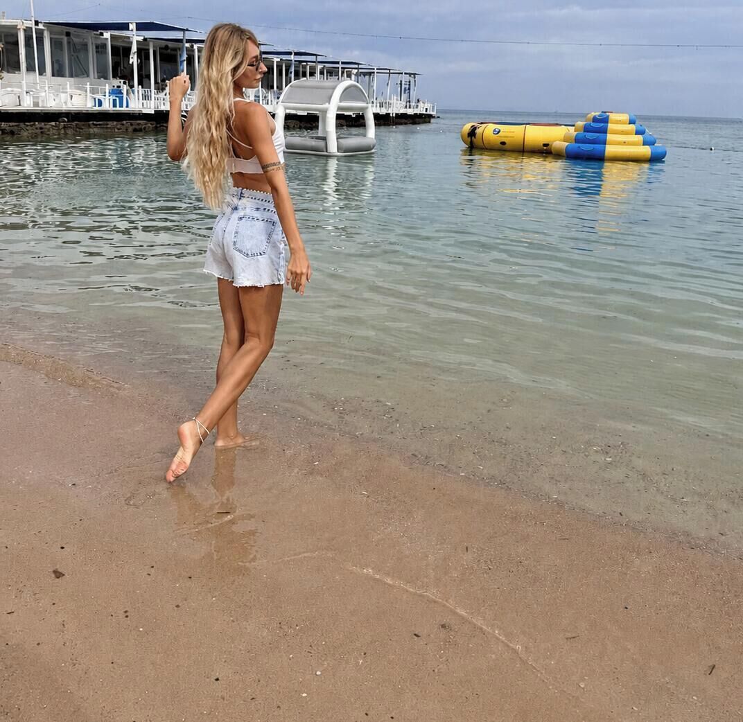 Una playa con agua cristalina, un muelle y una estructura flotante.