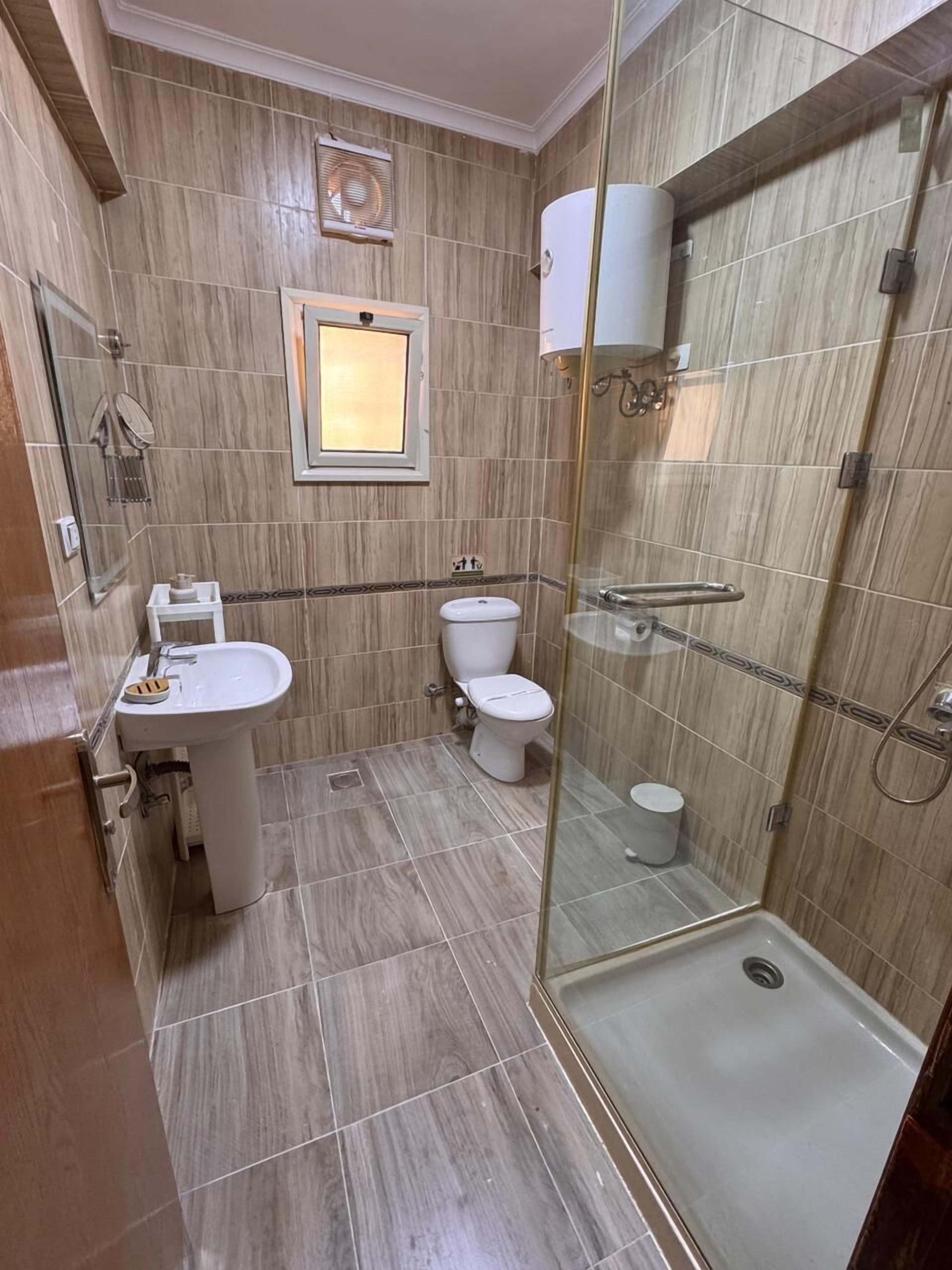 A bathroom with a glass-enclosed shower, a sink, and two toilets.