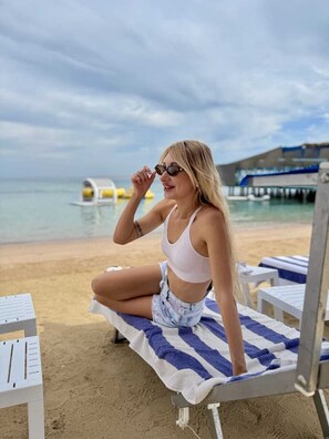 A beach chair with a towel, a clear view of the sea, and a building in the background. - Lilly Stay (Hurghada)