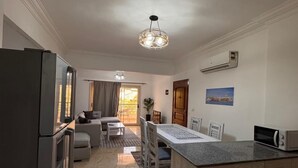 A modern kitchen with a marble floor, a central island, and a dining area with a sofa and table. - Lilly Stay (Hurghada)