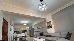 A living room with a sofa, a coffee table, and a dining area with a table and chairs. - Lilly Stay (Hurghada)