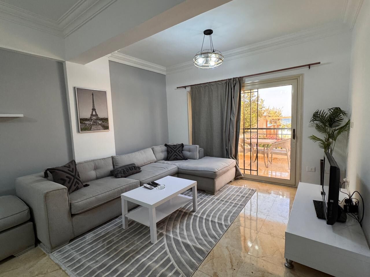 Una sala de estar moderna con un sofá modular, una mesa de centro blanca y un ventanal con cortinas.