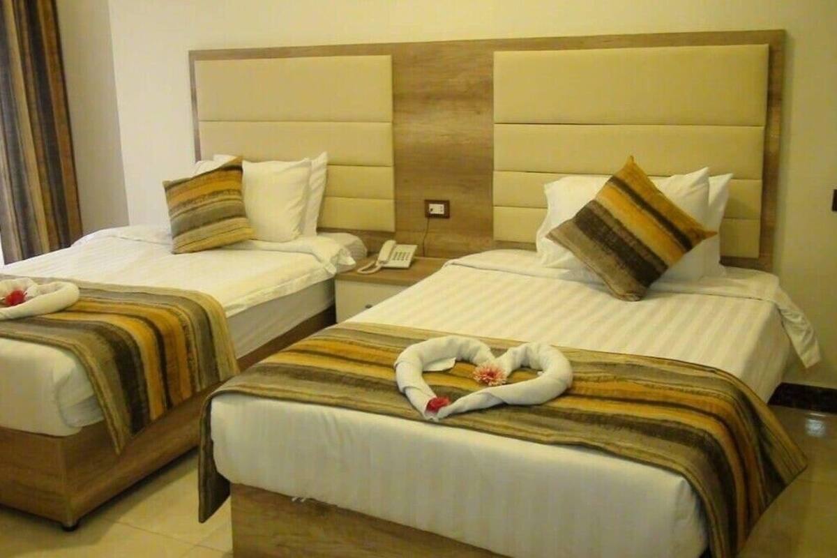 Dos camas individuales con cabeceras, un teléfono junto a la cama y un adorno con forma de corazón en el suelo.