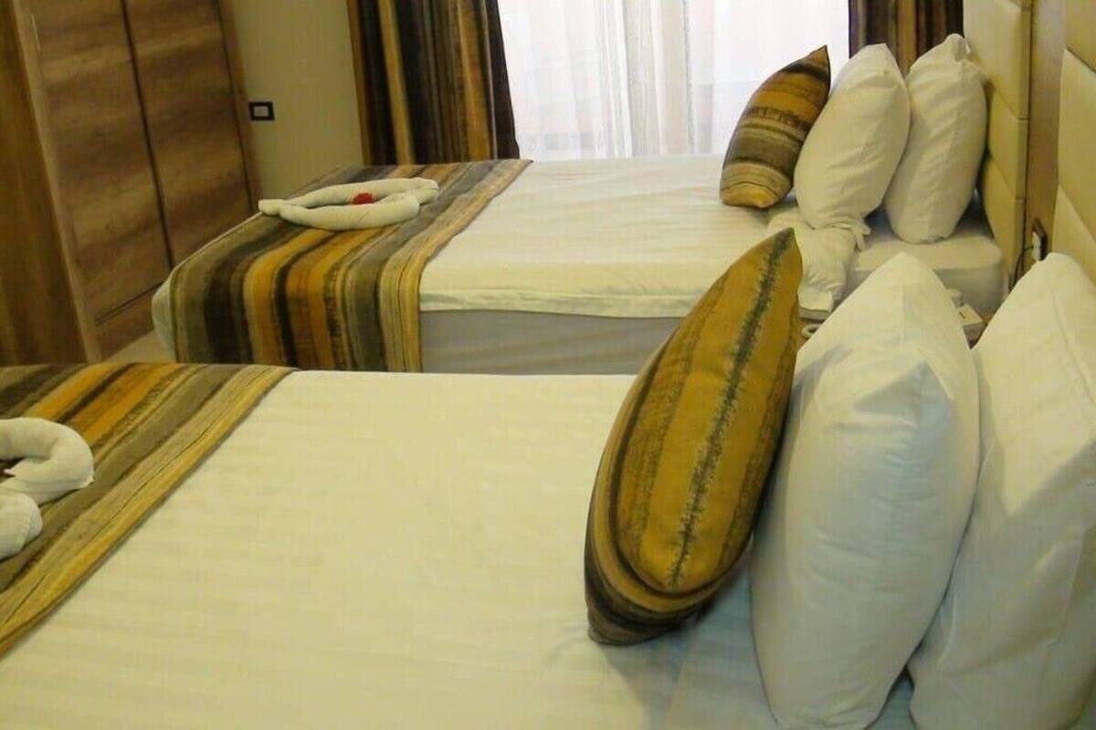 Habitación de hotel con dos camas, cada una con ropa de cama a rayas y numerosas almohadas.