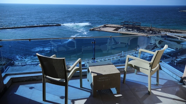 Un balcone con sedie in vimini e un tavolino che si affaccia sull'oceano.