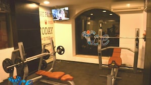 Una palestra con attrezzature per sollevamento pesi, un televisore a parete e un logo.