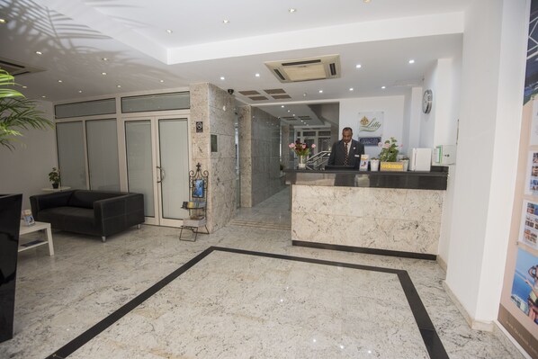 Welcome to our hotel lobby, featuring a reception desk, comfortable seating, and polished floors.