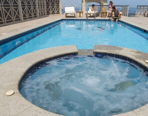 Relax by the pool with a hot tub and lounge chairs on the deck overlooking the ocean.
