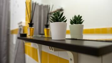 Uma bancada de cozinha com duas plantas em vasos, um porta-toalhas de papel branco e um revestimento de azulejos amarelo e branco.
