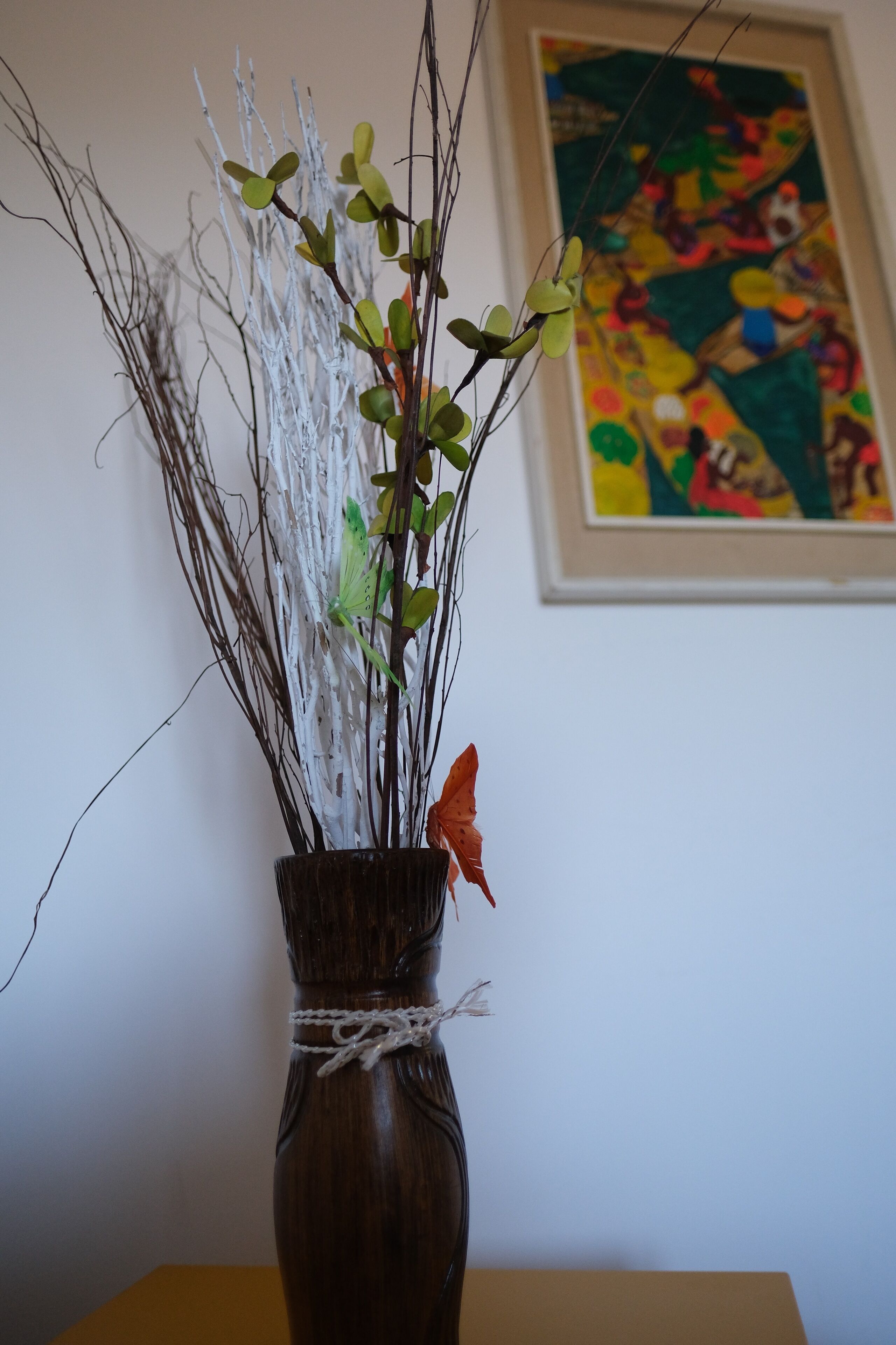 En vase med grene og blader på et bord.