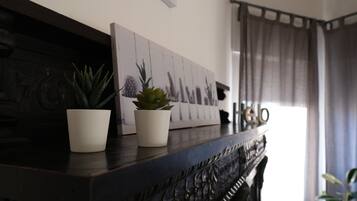 A dark wooden console table with two potted plants and a framed picture of cacti.