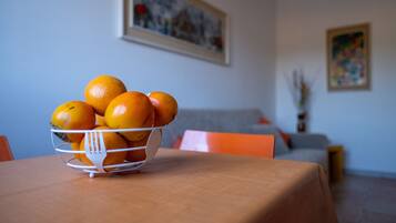 Uma mesa de jantar com uma cesta de frutas contendo laranjas.