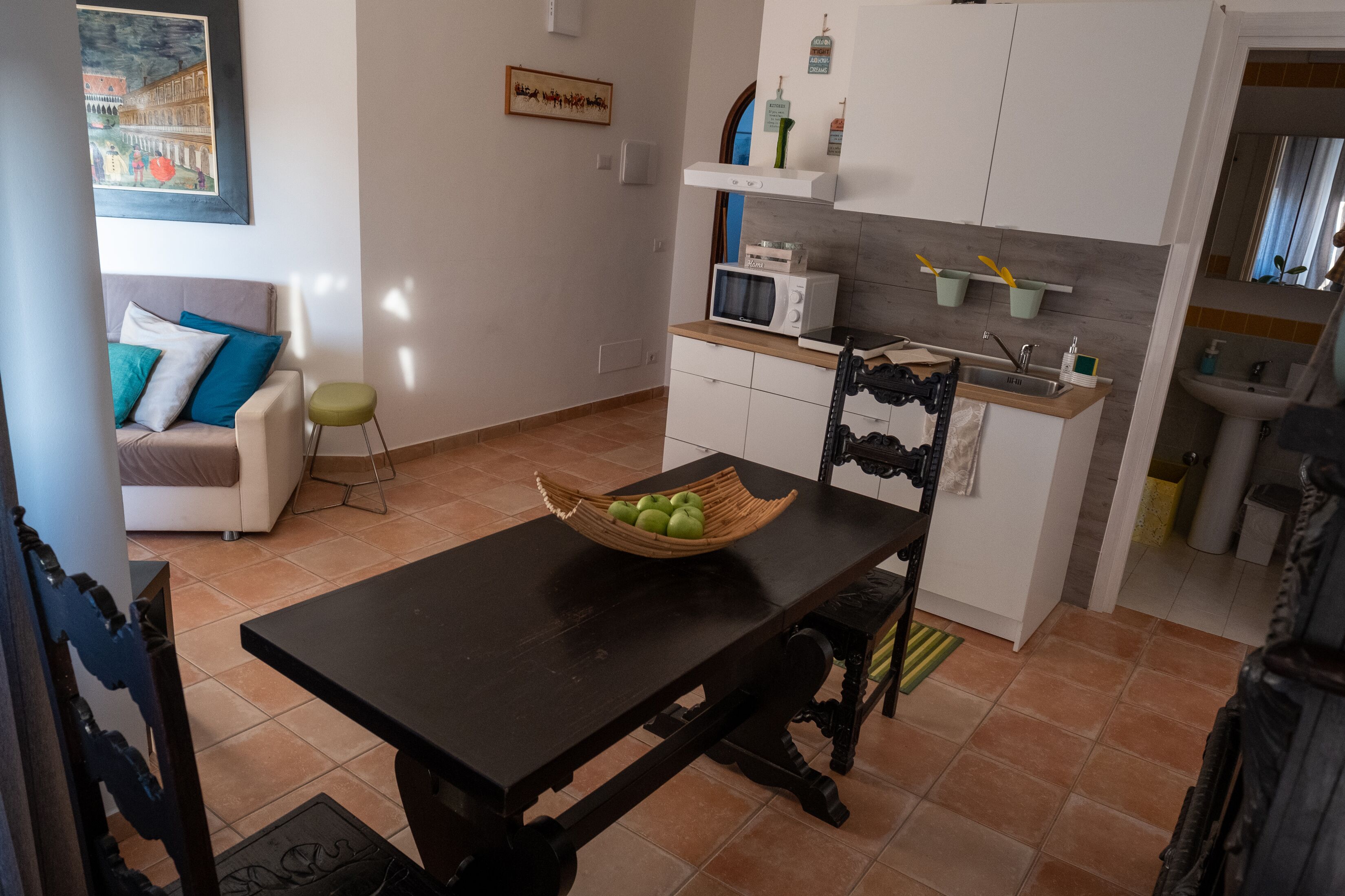 Un espacio habitable compacto con una mesa de comedor, un sofá, una zona de cocina con microondas y un fregadero.