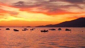 Un atardecer sobre un cuerpo de agua con numerosos barcos.
