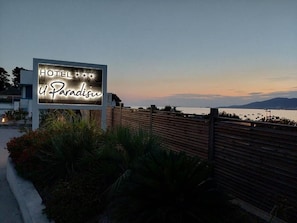 Un letrero de hotel con el nombre 'HOTEL U Paradise' sobre un cielo al anochecer.