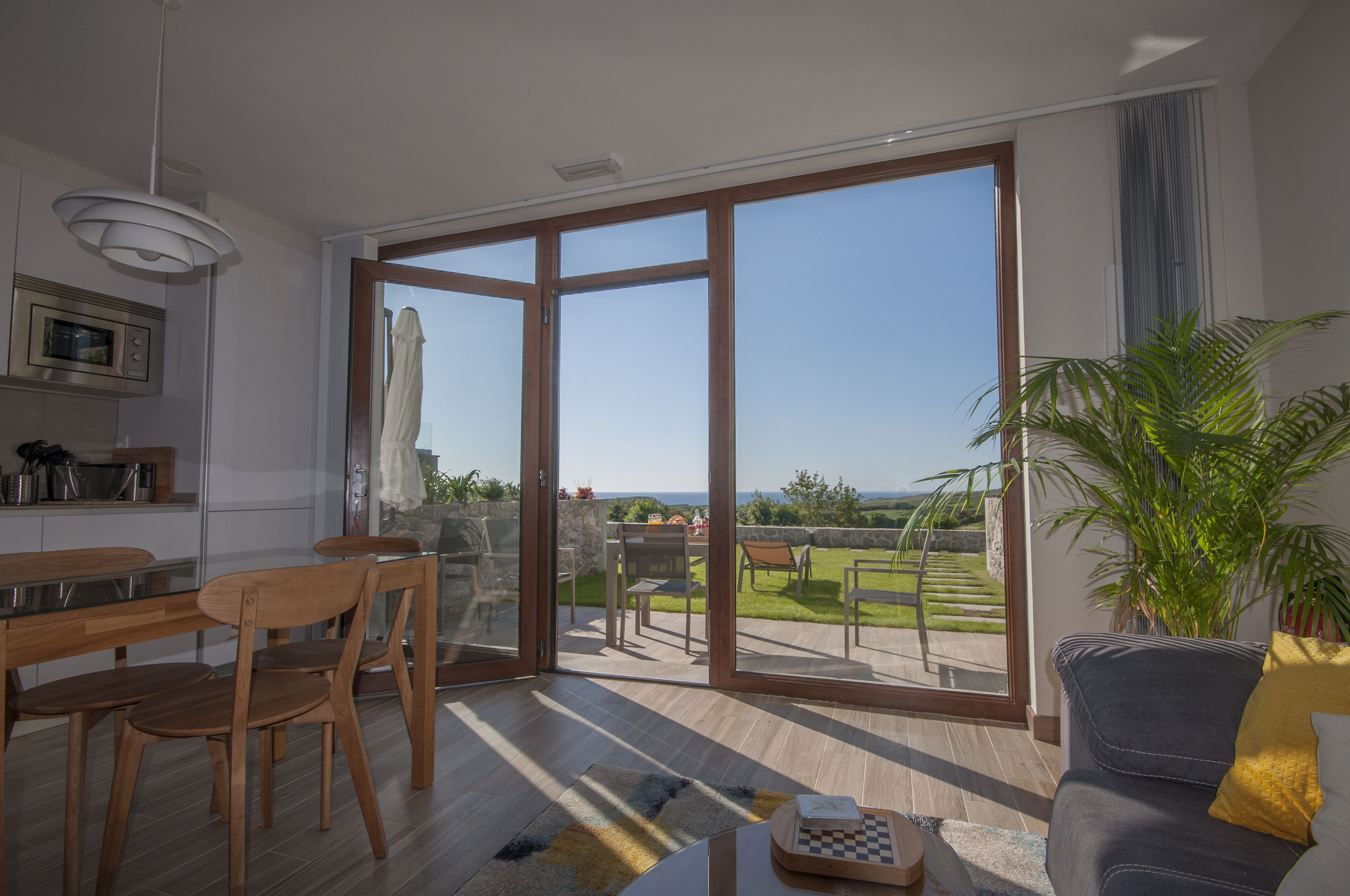 A modern living room with a large sliding glass door leading to a balcony with a view of the countryside.