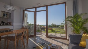 Ein modernes Wohnzimmer mit einem großen Schiebeglasfenster, das auf einen Balkon mit Blick ins Grüne führt.