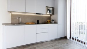 Eine moderne Küche mit weißen Schränken, einer Edelstahl-Mikrowelle und einem Holzschneidebrett.