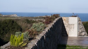 Eine steinerne Stützmauer mit Blick auf das Meer und die Ferne der Klippen.