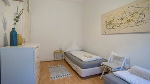 A small, neatly arranged bedroom with a bed, a chair, a small table, and a cabinet. - pestahome - Private Apartment Linden / Hanover, pestahome - Stadtwohnung in Linden (Hanover)