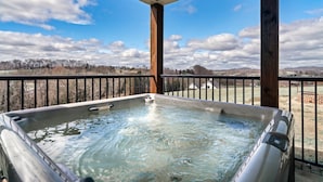A hot tub on a balcony with a view of a cloudy sky and distant landscape. - Stunning farmhouse with Mountain View’s! (Sevierville)