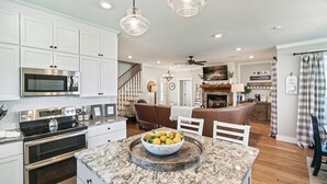 A modern kitchen with white cabinets, stainless steel appliances, and a marble countertop. - Stunning farmhouse with Mountain View’s! (Sevierville)