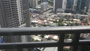 A high-rise building with multiple floors, large windows, and a view of a cityscape with various buildings and construction sites.