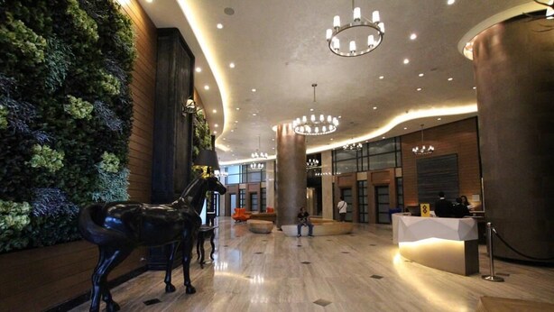 A lobby with a reception desk, a large chandelier, and a horse statue.