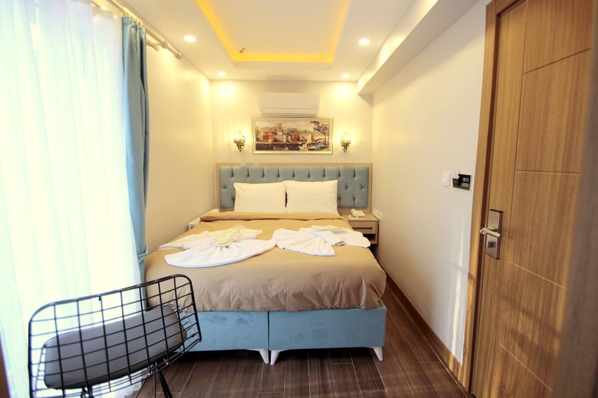 A neatly made bed with a headboard, a bedside table with a lamp, and a chair.