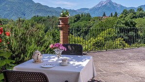 A table set outdoors with a view of mountains, a brick pillar, and a metal fence. - Splendid Liberty villa overlooking the lush green Tuscan valleys and mountains (Barga)