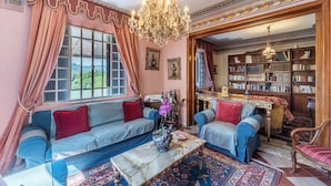 A cozy living room with a sofa, armchairs, a coffee table, and a bookshelf filled with books. - Splendid Liberty villa overlooking the lush green Tuscan valleys and mountains (Barga)