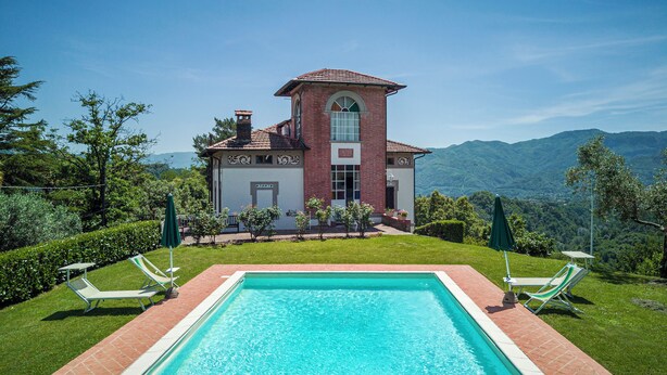 A swimming pool with a view of a large house and mountains in the background. - Splendid Liberty villa overlooking the lush green Tuscan valleys and mountains (Barga)