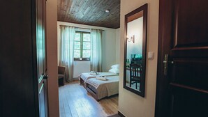 Un dormitorio con techo de madera, un espejo grande, una cama con dos almohadas y una ventana con cortinas.