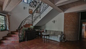 Un amplio salón con una escalera, un sofá, una mesita y una pared de ladrillo.