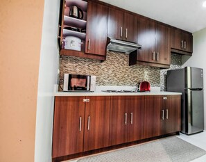 Una cocina con gabinetes de madera, un refrigerador de acero inoxidable, un microondas y un tostador.