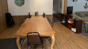 Ein Essbereich mit einem Holztisch und Stühlen, einer Wandmalerei und einem Fernseher in der Ecke.