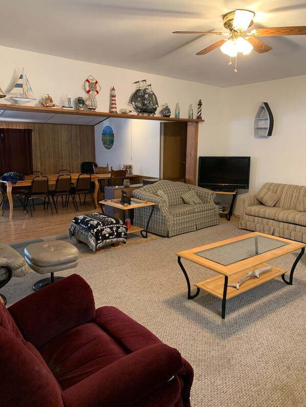 A living room with a TV, sofa, armchair, and a dining area with chairs and a table.